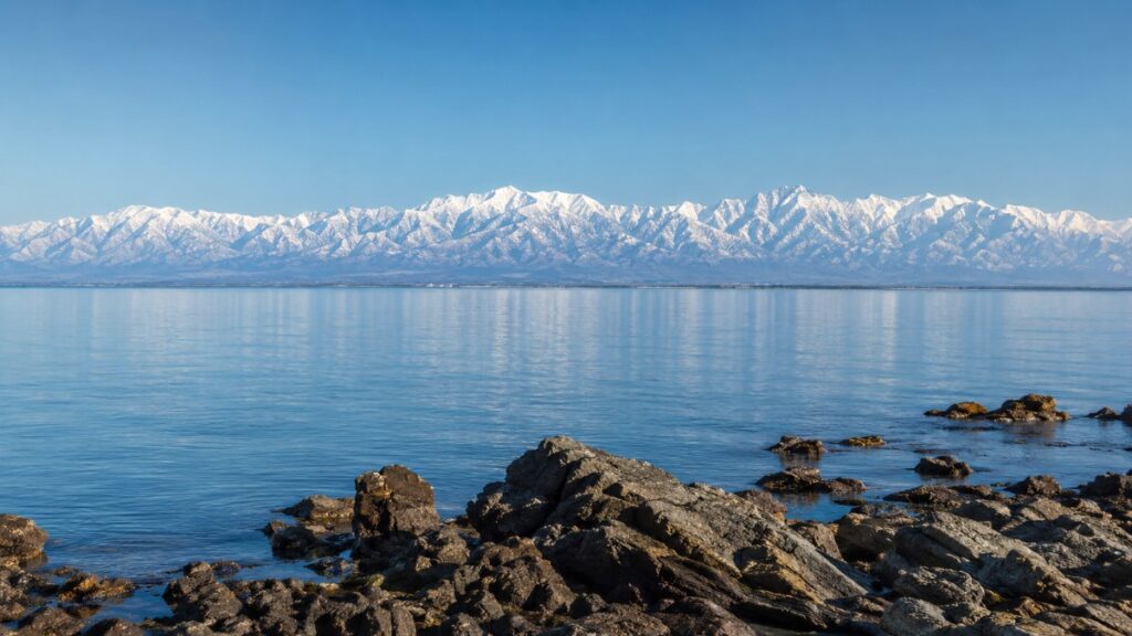 雨晴海岸の岩場越しに富山湾と冠雪した立山連峰を望む富山県の風景