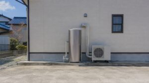 日本の戸建て住宅の外壁沿いに設置されたエコキュートの貯湯タンクとヒートポンプユニット