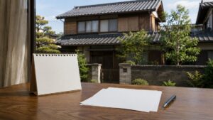 日本の住宅を背景にした卓上カレンダーと書類